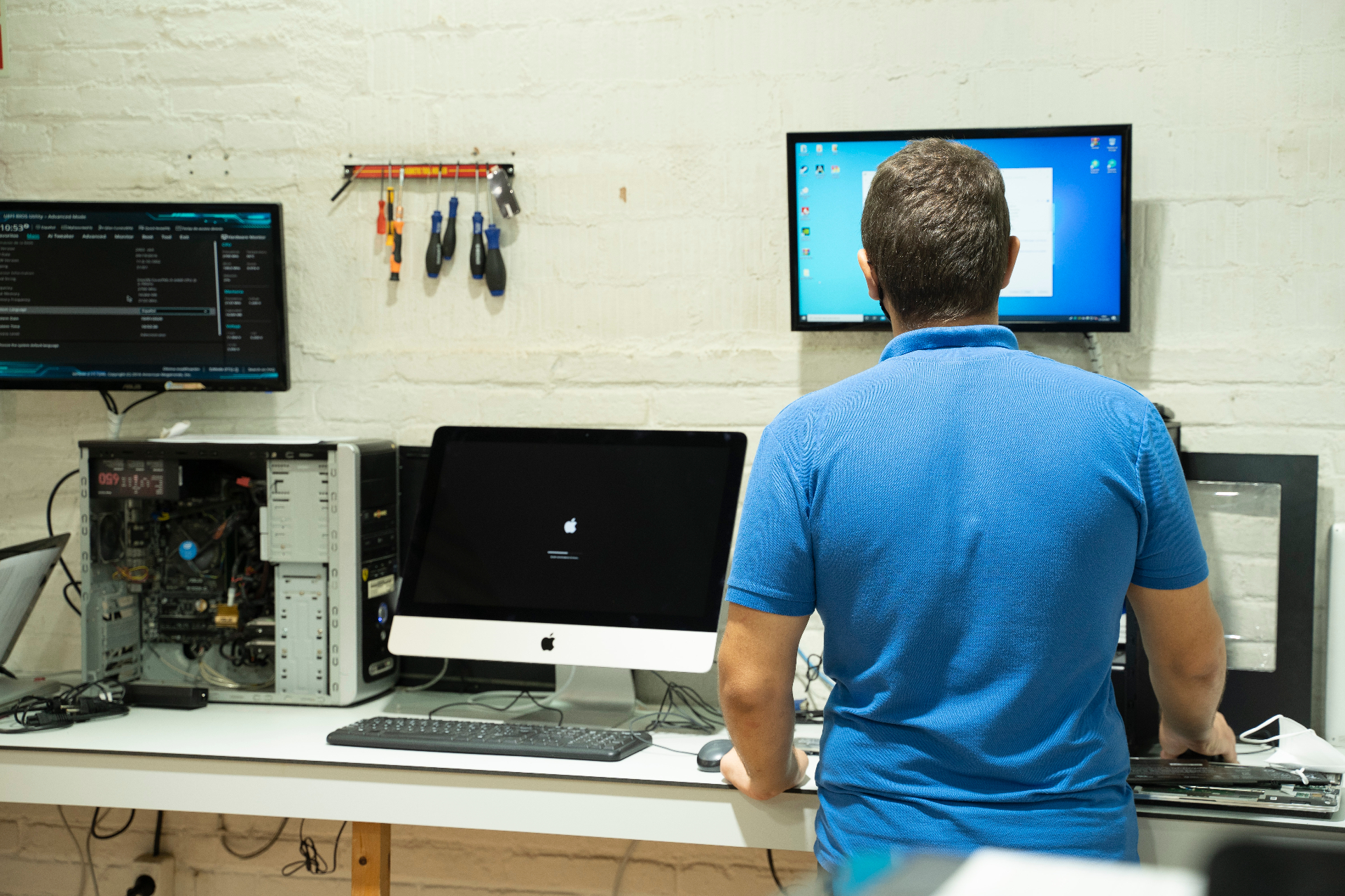 Tècnic d'Infosat reparant un ordinador de sobretaula i un iMac al taller de Vilafranca del Penedès